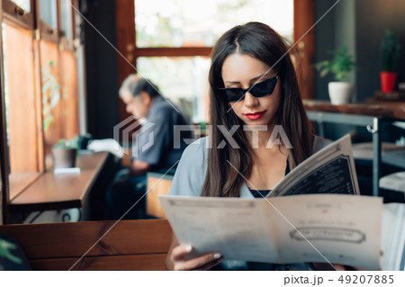 Attractive woman in sunglasses is sitting in a restaurant. Attractive woman in sunglasses is sitting in a restaurant. 49207885