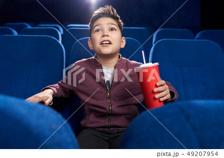 Fascinated teenager watching movie attentively in cinema. Fascinated teenager watching movie attentively in cinema. 49207954