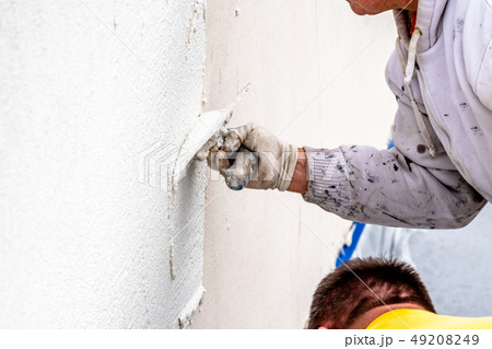 Construction worker plastering and smoothing concrete wall with cement 49208249