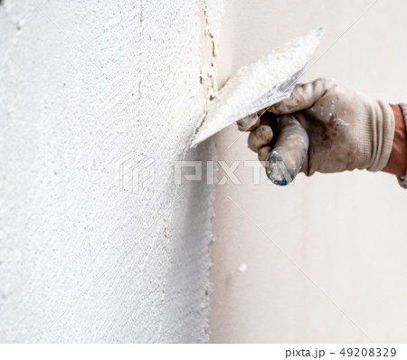 Construction worker plastering and smoothing concrete wall with cement 49208329
