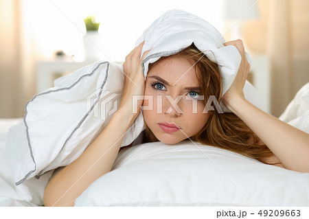 Young beautiful woman lying in bed suffering with insomnia Young beautiful woman lying in bed suffering with insomnia 49209663