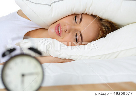 Young beautiful blonde woman lying in bed suffering from alarm clock sound 49209677