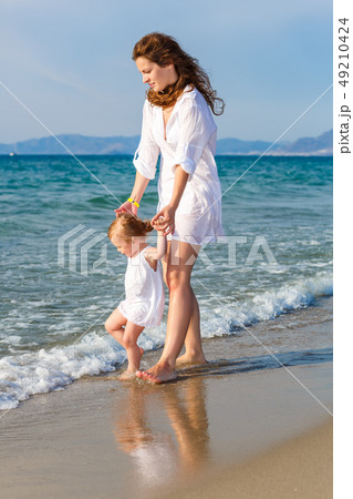 Mother and daughter walking on the beach Mother and daughter walking on the beach 49210424