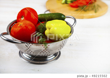 Tomatoes, peppers and cucumbers in a colander on a Tomatoes, peppers and cucumbers in a colander on a 49215502
