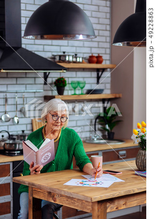 Attractive aged female considering vedic tables sitting at kitchen table Attractive aged female considering vedic tables sitting at kitchen table 49228863