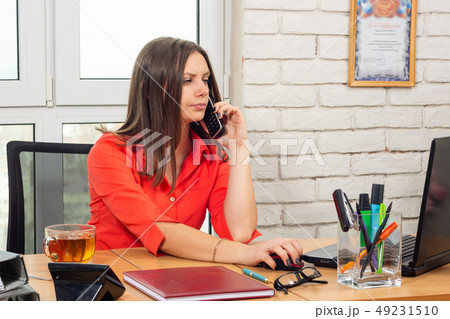 An office employee is talking on the phone and 49231510