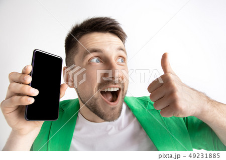 Young handsome man showing smartphone screen and signing OK isolated on gray background 49231885