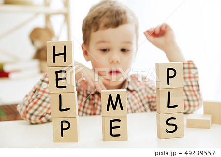 Wooden cubes with words HELP ME PLS in hands of little boy 49239557