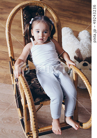 a little girl in a dress sits on a chair and 49243236