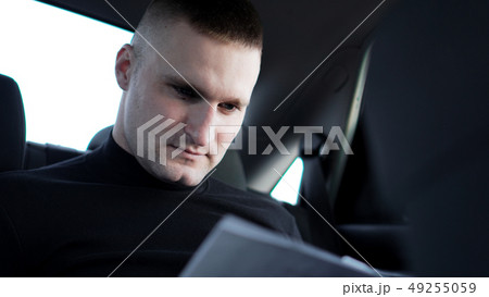 Businessman looking through documents while sitting at the back of a car 49255059