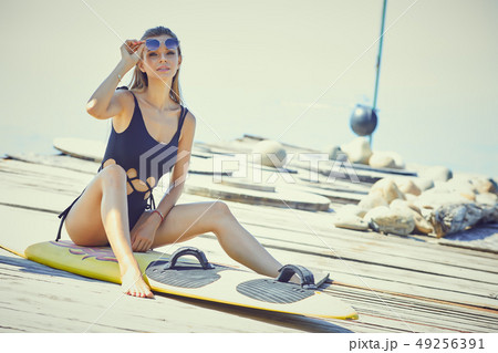 Young woman in wetsuit with surfing board standing 49256391