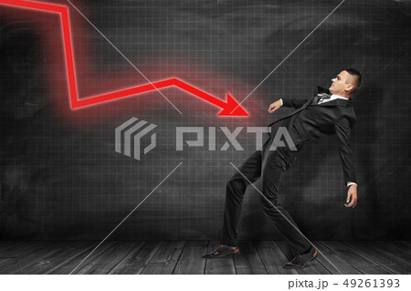Side view of businessman in black suit leaning backwards trying to dodge red graph arrow pointing at Side view of businessman in black suit leaning backwards trying to dodge red graph arrow pointing at 49261393