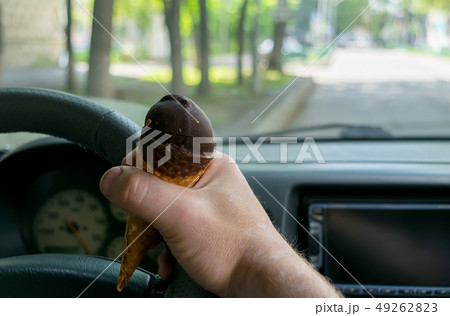 the driver holds the ice cream while driving a car the driver holds the ice cream while driving a car 49262823