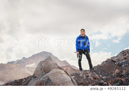 Portrait of a professional guide of a mountaineer in a cap and sunglasses with an ice ax in his hand 49265112