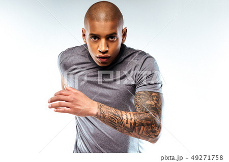 Sportive bold tattoed man performing running movements Sportive bold tattoed man performing running movements 49271758
