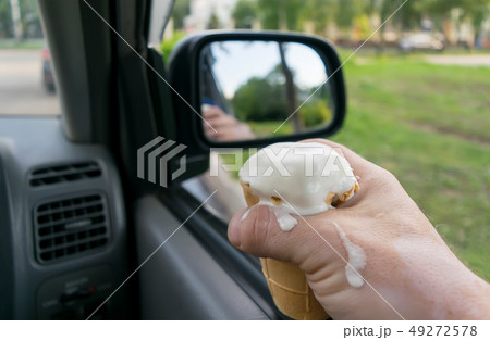 the driver holds the ice cream while driving a car 49272578