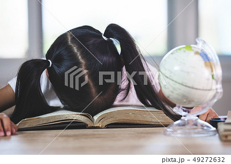 Tired asian child girl sleeping over the book Tired asian child girl sleeping over the book 49272632