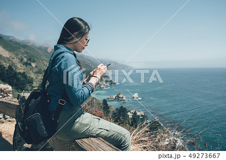 backpacker sits on railing on top of mountain 49273667