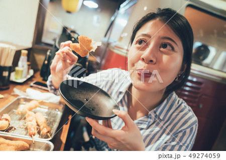 woman holding plate of kushikatsu eating 49274059