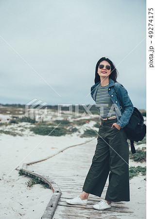 woman standing on wooden walkway near beach woman standing on wooden walkway near beach 49274175