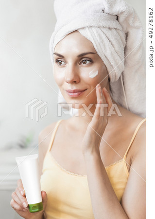 Girl applies face cream. Skin care and beauty concept. Young woman applying moisturizer on her face 49278162