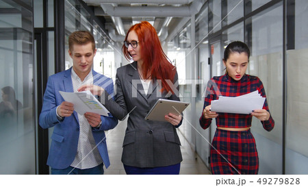 Business people walking through the corridor abd showing the documents to their woman chief 49279828