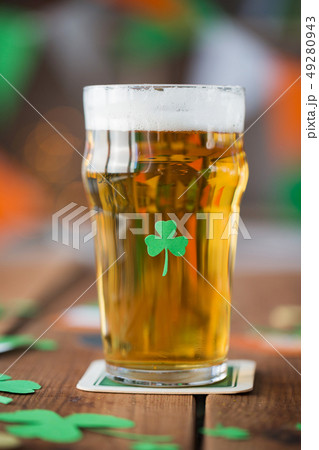 close up of glass of beer with shamrock on table 49280943