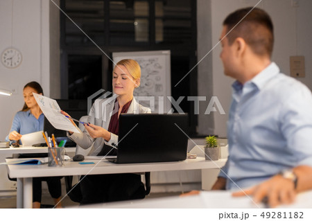 woman showing charths to colleague at night office 49281182