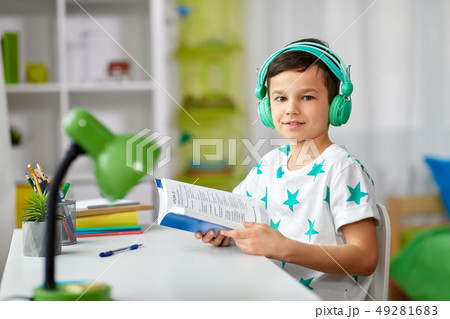 boy in headphones with textbook learning at home boy in headphones with textbook learning at home 49281683