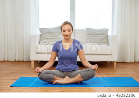 woman meditating in lotus pose at home woman meditating in lotus pose at home 49282206