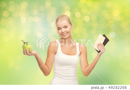 woman choosing between green apple chocolate woman choosing between green apple chocolate 49282208