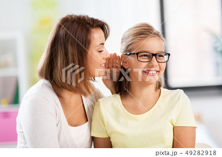 happy mother whispering secret to daughter at home happy mother whispering secret to daughter at home 49282918