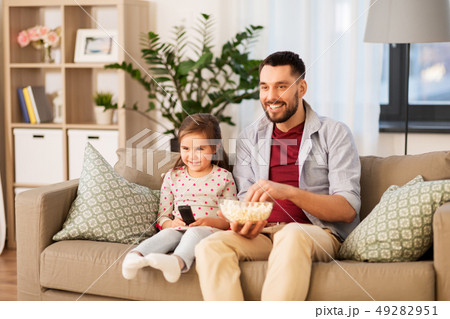 happy father and daughter watching tv at home 49282951