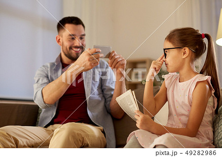 father photographing daughter by cellphone at home father photographing daughter by cellphone at home 49282986