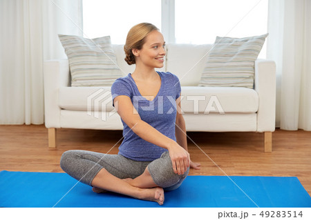 woman doing twist in lotus pose at home woman doing twist in lotus pose at home 49283514