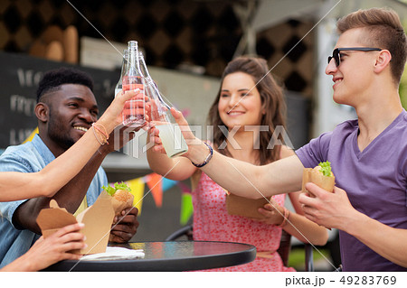 friends clinking drinks and eating at food truck 49283769