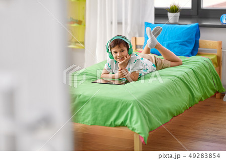 smiling boy with tablet pc and headphones at home smiling boy with tablet pc and headphones at home 49283854
