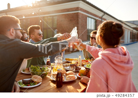 happy friends toasting drinks at rooftop party 49284357