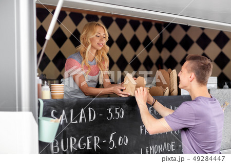 saleswoman at food truck serving male customer saleswoman at food truck serving male customer 49284447