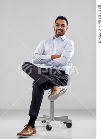 smiling indian businessman sitting on office chair smiling indian businessman sitting on office chair 49285189