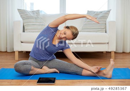 woman with tablet computer doing yoga at home woman with tablet computer doing yoga at home 49285367