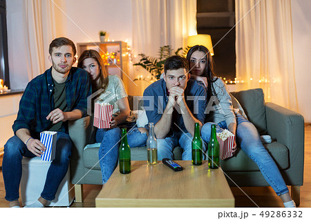 friends with beer and popcorn watching tv at home 49286332