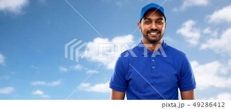happy indian delivery man in blue uniform over sky happy indian delivery man in blue uniform over sky 49286412