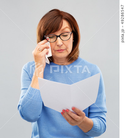 sad senior woman reading letter and crying sad senior woman reading letter and crying 49286547