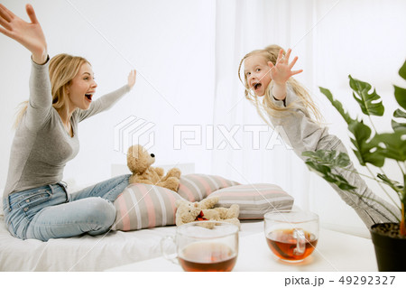 Young mother and her little daughter hugging and kissing on bed 49292327
