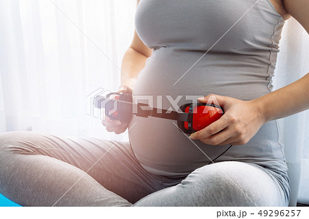 Pregnant woman letting baby in belly listen to music over window view 49296257
