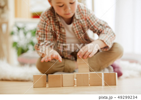 Little child sitting on the floor. Pretty boy palying with wooden cubes at home 49299234