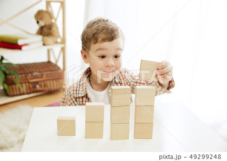 Little child sitting on the floor. Pretty boy palying with wooden cubes at home Little child sitting on the floor. Pretty boy palying with wooden cubes at home 49299248