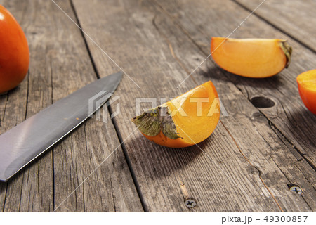 Particle of persimmon with knife on retro wooden table 49300857