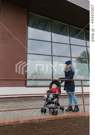 A woman stands near a shopping center with a A woman stands near a shopping center with a 49305007